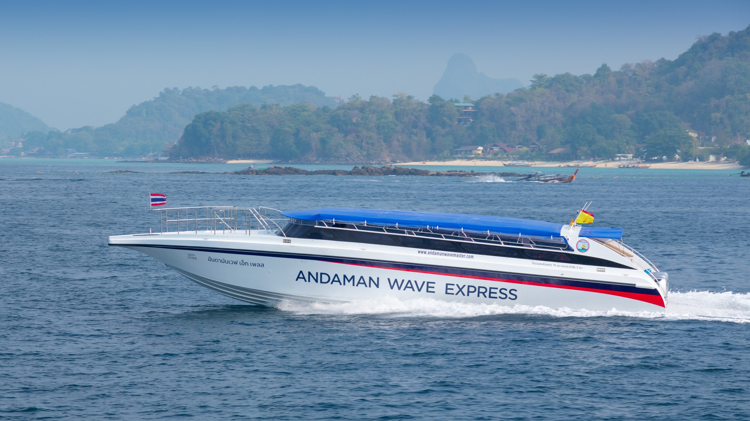 Speedboat named 'Andaman Wave Express' traveling on the ocean with hills in the background.