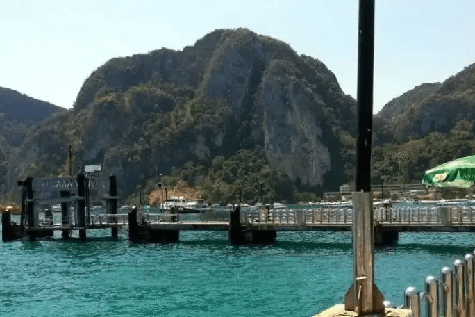 Scenic view of a pier and turquoise water with mountains in the background.