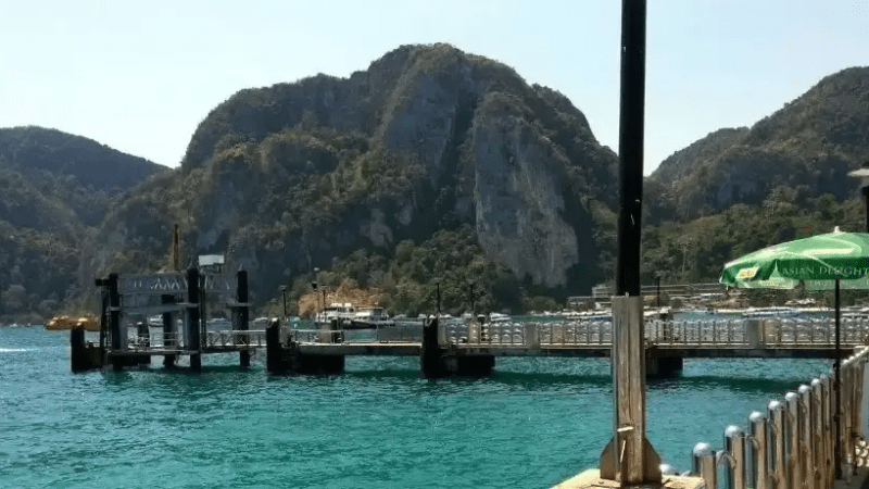 Scenic view of a pier and turquoise water with mountains in the background.