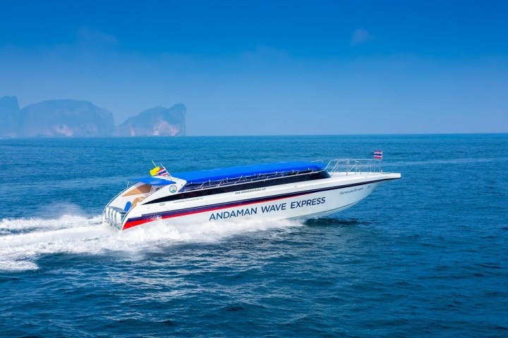 Speedboat 'Andaman Wave Express' cruising on the ocean with distant islands.