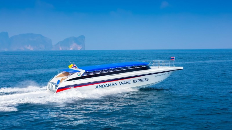 Speedboat 'Andaman Wave Express' cruising on the ocean with distant islands.