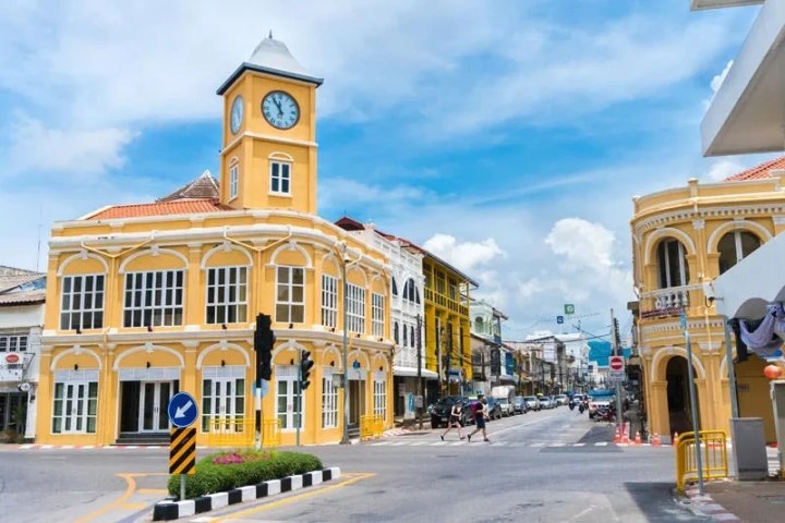 Yellow colonial-style building with a clock tower on a sunny day at a street corner.