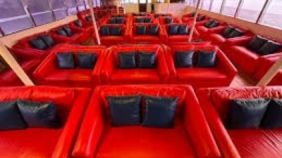 Interior view of a boat with rows of red cushioned seating and blue pillows.