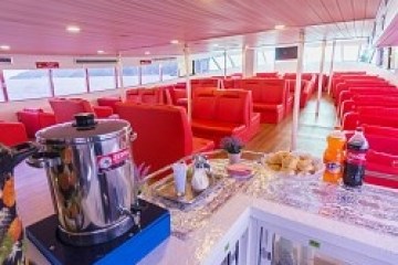 Interior of a ferry with red seating and a snack bar with drinks and pastries.