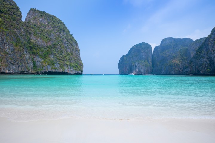 Idyllic beach with turquoise water and rocky cliffs under a clear blue sky.