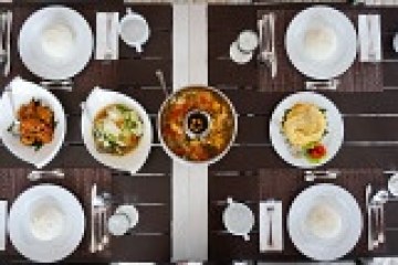 Table set with white plates, cutlery, and assorted dishes at the center.