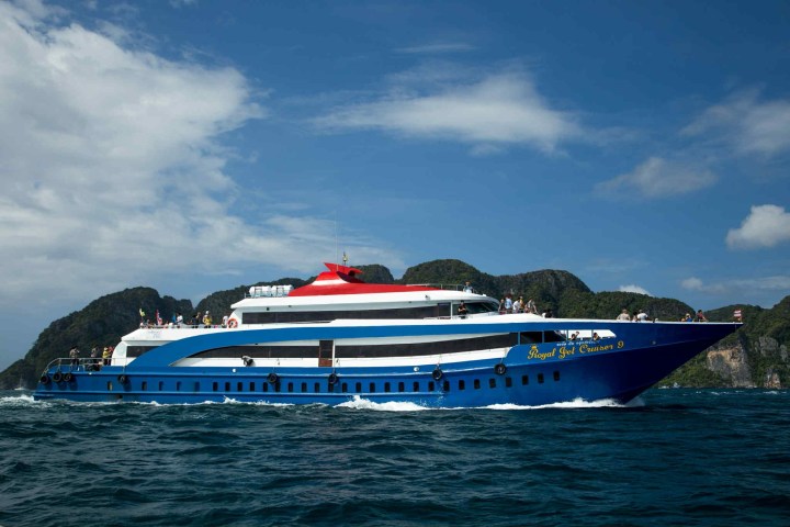 Blue and white ferry cruising on clear water with islands in background.