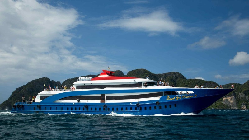 Blue and white ferry cruising on clear water with islands in background.