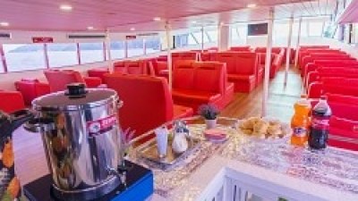 Ferry interior with red seats, beverage station, and snacks on a counter.