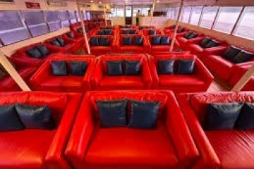 Interior of a boat with red seating and blue pillows in rows.