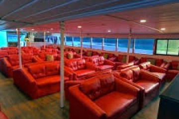Interior of a room with rows of red sofas and a wooden floor.