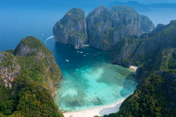Aerial view of a turquoise bay surrounded by steep cliffs with a sandy beach.
