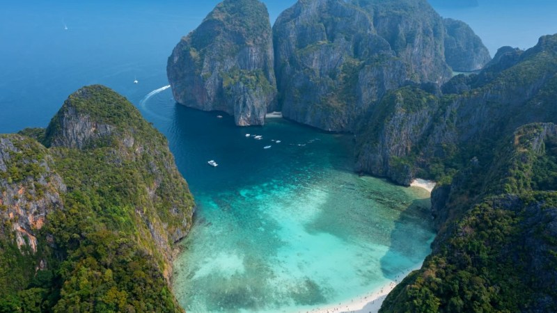 Aerial view of a turquoise bay surrounded by steep cliffs with a sandy beach.