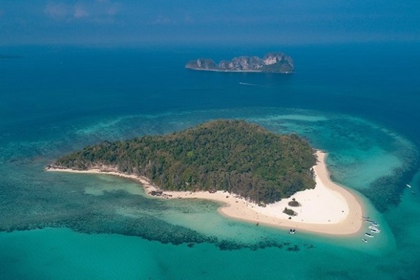 Aerial view of a lush green island with sandy beaches surrounded by turquoise waters.