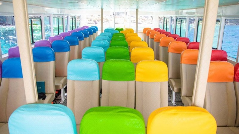 Bus interior with seats in vibrant colors: purple, blue, green, yellow, orange, and red.