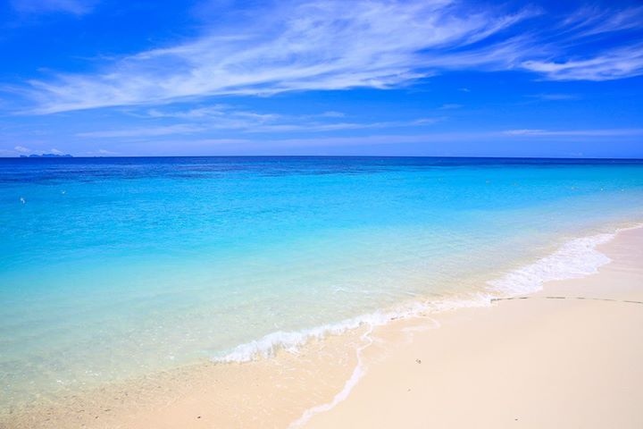 Sunny beach with turquoise water and clear blue sky.