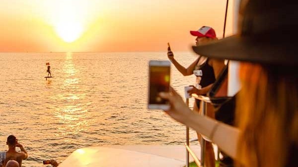 People on a boat taking photos of a sunset over the ocean.