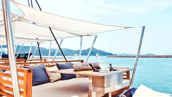 Daybed with pillows on a luxurious yacht deck against a scenic ocean backdrop.