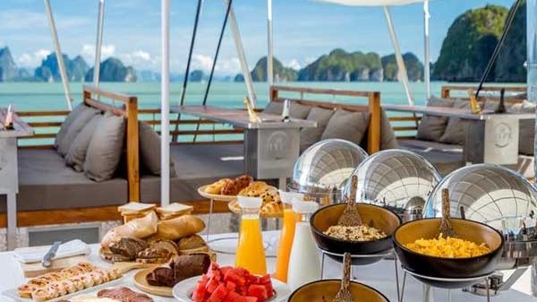 Buffet on a yacht deck with assorted foods, juice, and sea view.